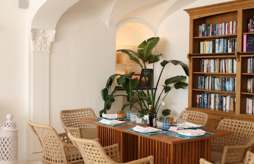 Sala da pranzo elegante con sedie intrecciate e libreria.